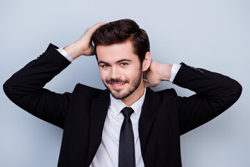Portrait of good-looking with beaming smile man dressed in black suit touching his perfect hair