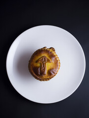 Small decorative mushroom pie with golden crust isolated on black background
