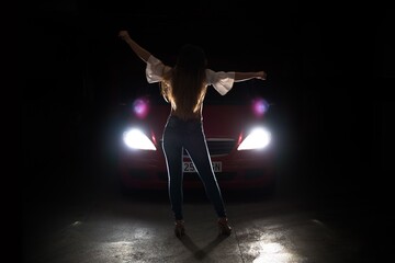Urban young girl with a car in dark parking