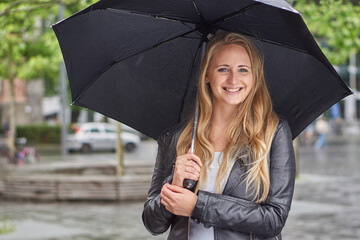 Blonde Frau mit Schirm im Regen
