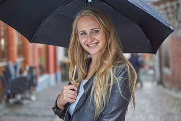 Blonde Frau mit Schirm im Regen