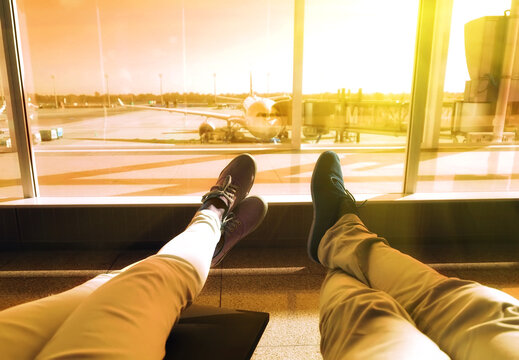 young couple waiting for the plane at an airport. humans legs with the plane on the background. Travel concept. Vintage colored picture             