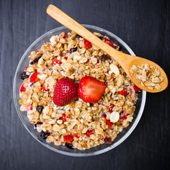 Muesli with strawberries and blueberries on dark table. Diet breakfast. Flat lay, top view