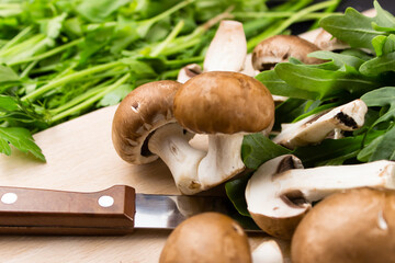 Fresh raw mushrooms brown mushrooms and green arugula on a wooden background. Shiitake Selective focus