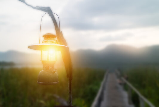 focus on the lantern amb which hang over the bamboo path way alongside papyrus to the lake with mountain view with fake lighting