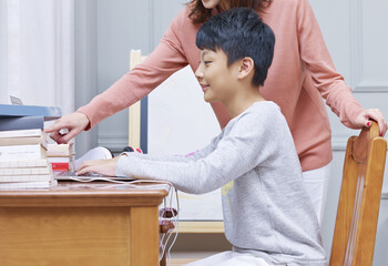 Asian mother mentoring her son doing homework at home
