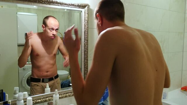 Young man checking his look in front mirror in bathroom. thin guy looking at the mirror.