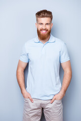 Obraz premium Successful stylish young red bearded man in casual wear is standing on the pure background, has a beaming smile