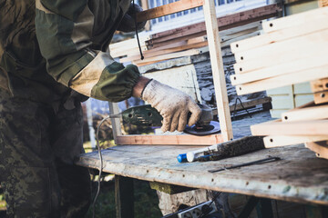 Man with grinding machine makes frame for bees. Create bee frame with your hands.