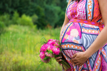 Photo of the belly of a pregnant woman in nature.