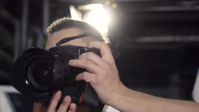 A young photographer in glasses takes in a dark room on a wide angle lens with flash. Smiles and builds a model. Close-up slow motion.