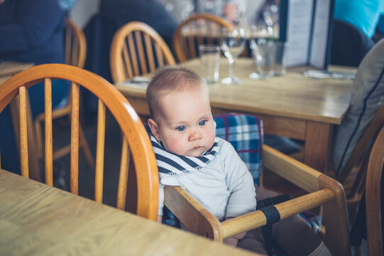 Cute little baby sitting at table in restaurant