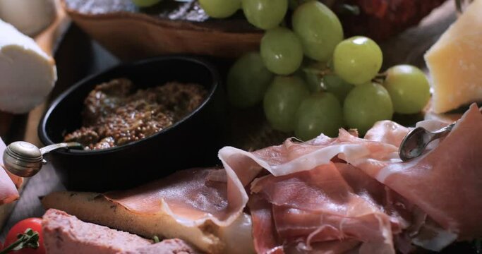 Dolly close up push out view of a platter of cured meat (charcuterie), ham, salami, pate and cheese