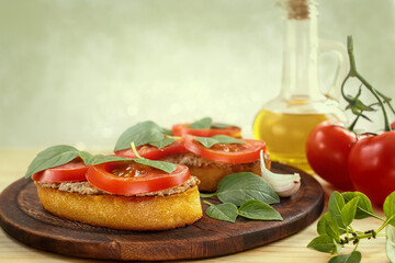 Bruschetta with liver pate, tomatoes and basil on a wooden board. Traditional Italian snack. Close-up.