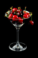 Kirschen im Cocktailglas vor schwarzem Hintergrund