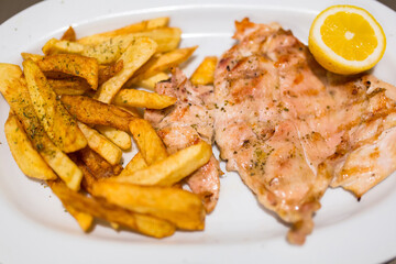 Grilled chicken fillet with french fries on the plate