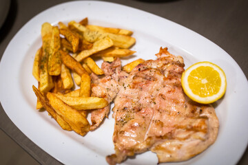 Grilled chicken fillet with french fries on the plate