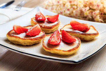 pancakes with strawberries on a beautiful plate stand on the table