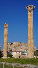 Fototapeta na wymiar Photo of iconic pillars of Temple of Olympian Zeus with view to the Acropolis and the Parthenon, Athens historic center, Attica, Greece 