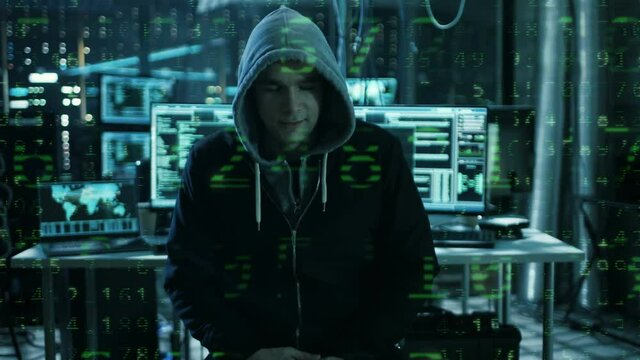 Dangerous Internationally Wanted  Hacker Speaks into the Camera with Raining Numbers Code Effect. In the Background His Operating Room with Multiple Displays and Cables.