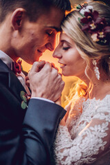 bride and groom kissing in the forest. Newlyweds embrace each other in park with lights and fantastic atmosphere.