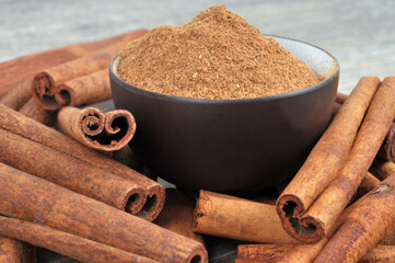Bol de cannelle en poudre entouré de bâtons de cannelle