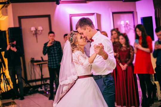 Happy newlyweds dancing in the restaurant hall. Bride and groom kiss.