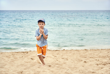 Fototapeta na wymiar Cute European Boy is running over the sand on the beach. He is running towards the camera.