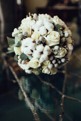 Obraz na płótnie Canvas Wedding bouquet made of roses and decorative silver berries and cotton lies on glass table