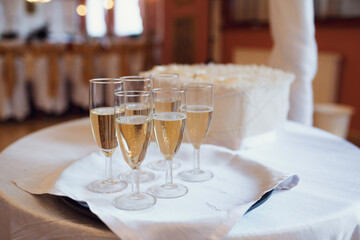 Champagne flutes stand on tray on white table