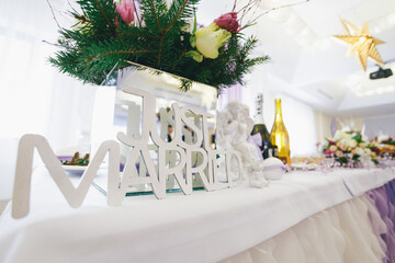 White lettering 'Just married' stands before porcelain angels on dinner table