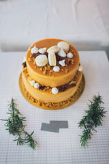 Tired cake decorated with white macaroons and yellow glaze