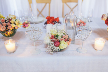 Long dinner table for wedding couple decorated with little bouquets and thick candles