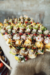 Dish with tasty snacks on sticks served on hessian cloth