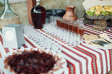 Empty glass shots and plates with snacks served on embroidered cloth