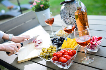 Obraz na płótnie Canvas holiday summer brunch party table outdoor in a house backyard with appetizer, glass of rosé wine, fresh drink and organic vegetables