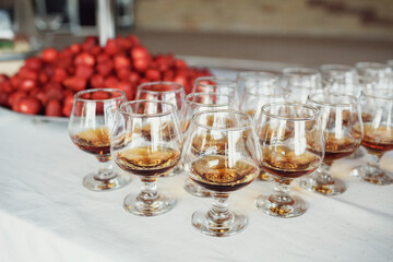 Many cherries served on large steel dish stand behind glasses with whisky