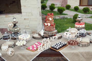 Wooden lettering 'Candy bar' stands before tired wedding cake with berries