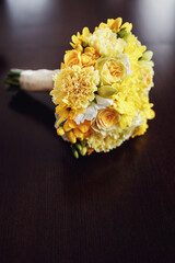 Yellow wedding bouquet lies on the dark table