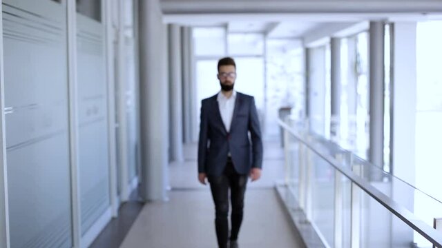Businessman walking trought company building then stops and cross arms