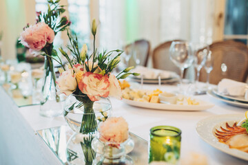 Little bouquets of peonies stand on white dinner table