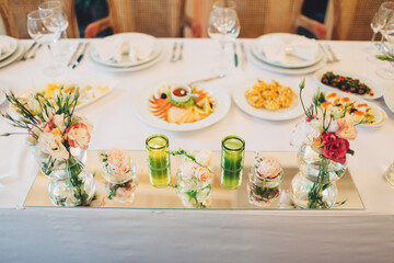 Little bouquets of peonies stand on white dinner table