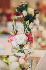 Little bouquets of pinks stands on the dinner table