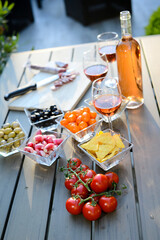 holiday summer brunch party table outdoor in a house backyard with appetizer, glass of rosé wine, fresh drink and organic vegetables