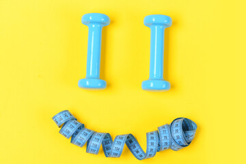 measuring tape and barbell or dumbbells on yellow
