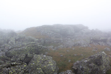 Gloomy mountain landscape. Fog in the mountains, the gloom comes down from the mountains. Mountain placer in the fog.
