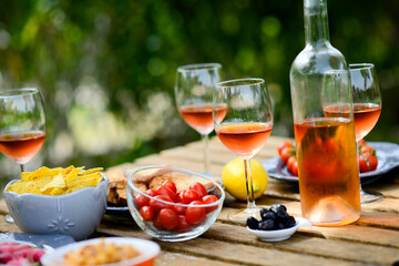 holiday summer brunch party table outdoor in a house backyard with appetizer, glass of rosé wine, fresh drink and organic vegetables