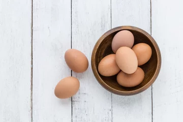 Fotobehang Eieren eggs in a wooden bowl on old wooden table top view  © suriya