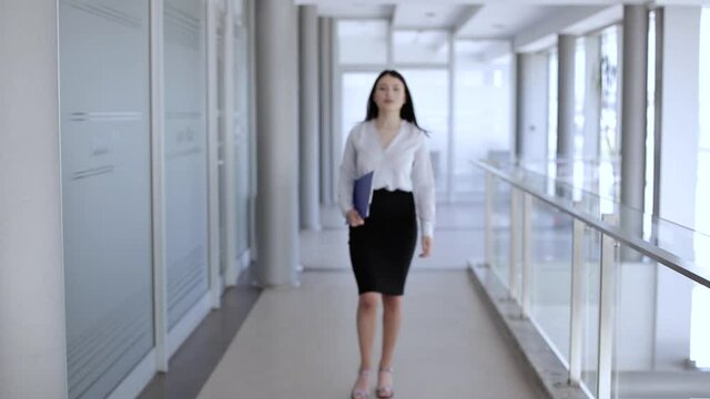 Attractive woman walking and holding paperboard,stops and smile to camera