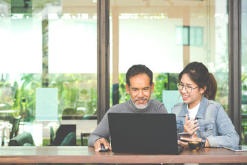 Fototapeta na wymiar Smiling Attractive mature man with white stylish short beard using tablet with charming woman teenage. Serving internet via his gadget. Teaching old man using social network technology